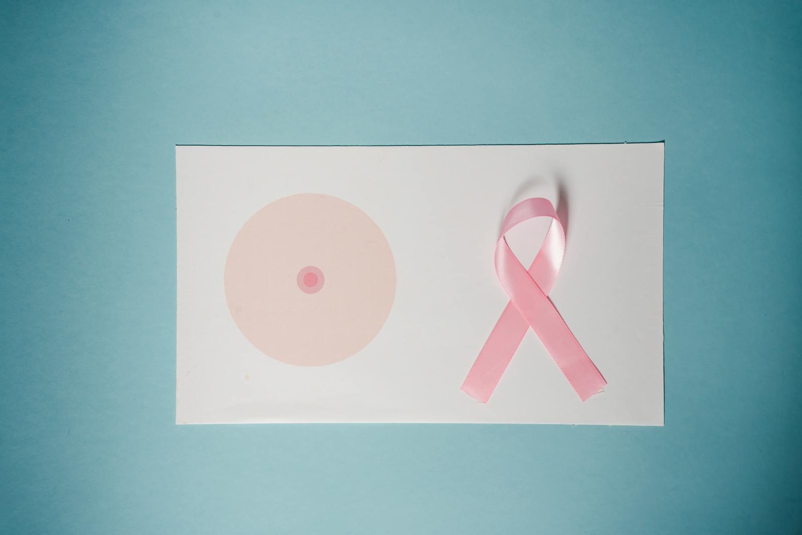 Breast cancer awareness concept with pink ribbon on pastel background.